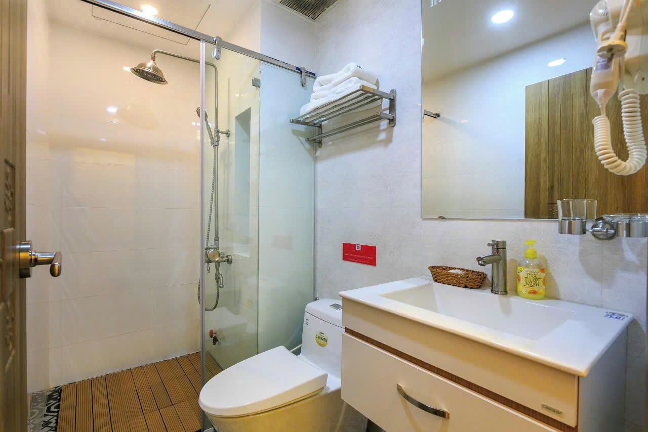 A modern bathroom with a glass shower enclosure, a toilet, a sink with a mirror, and a towel rack.