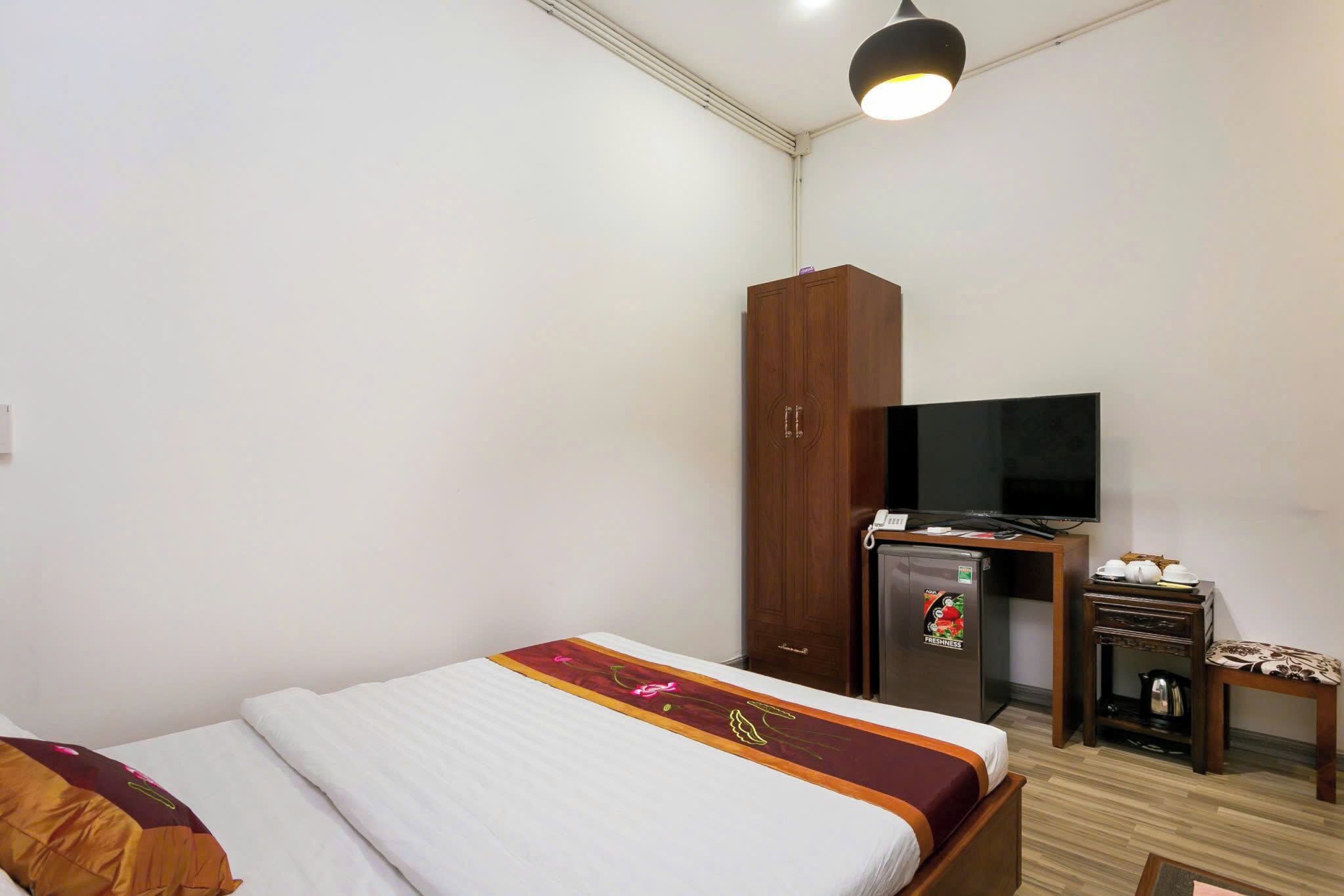 Ein Hotelzimmer mit Bett, Kleiderschrank, Schreibtisch mit Fernseher und kleinem Tisch mit Wasserkocher.