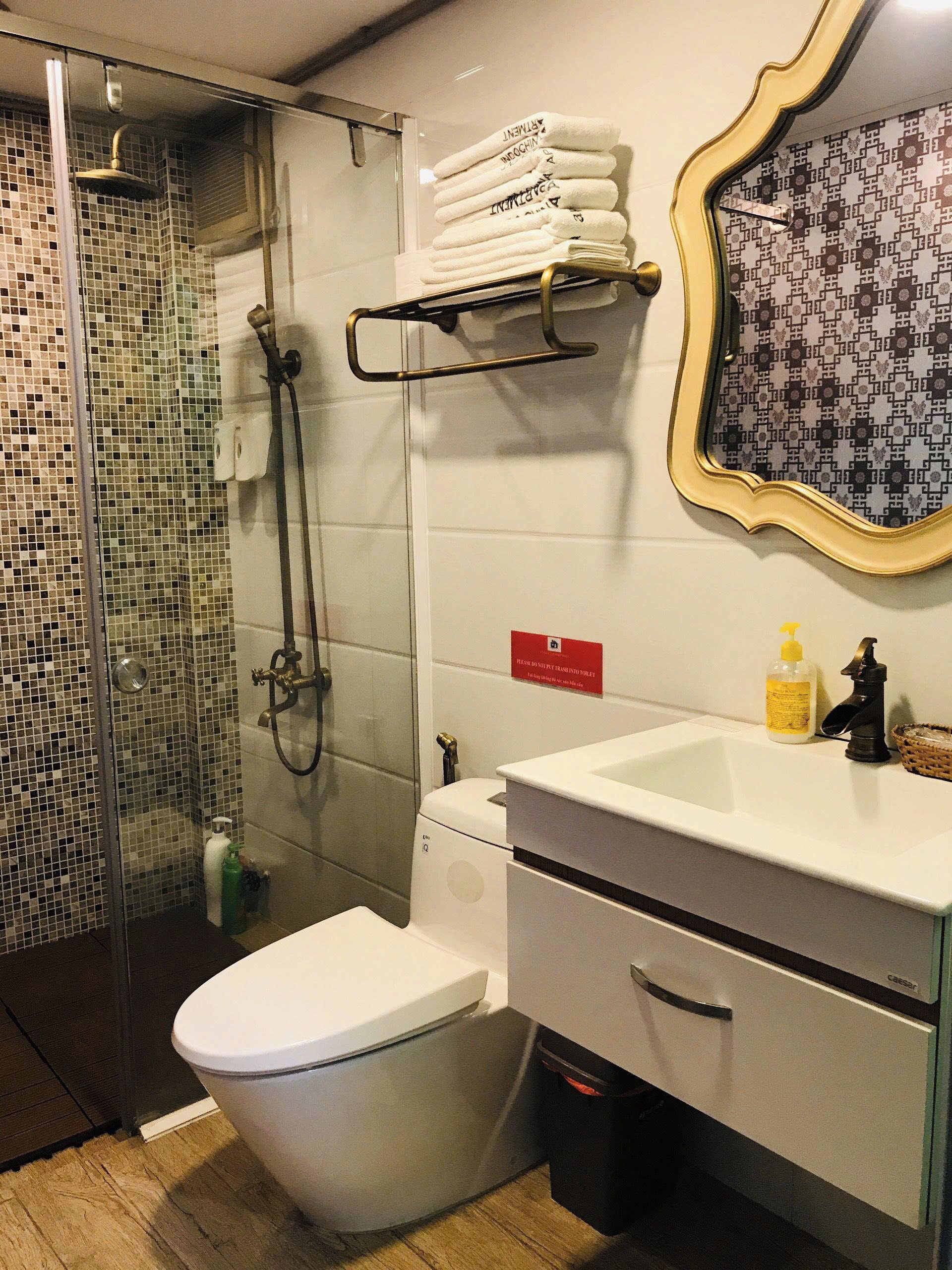 A bathroom with a shower, toilet, sink, and a towel rack with neatly folded towels.
