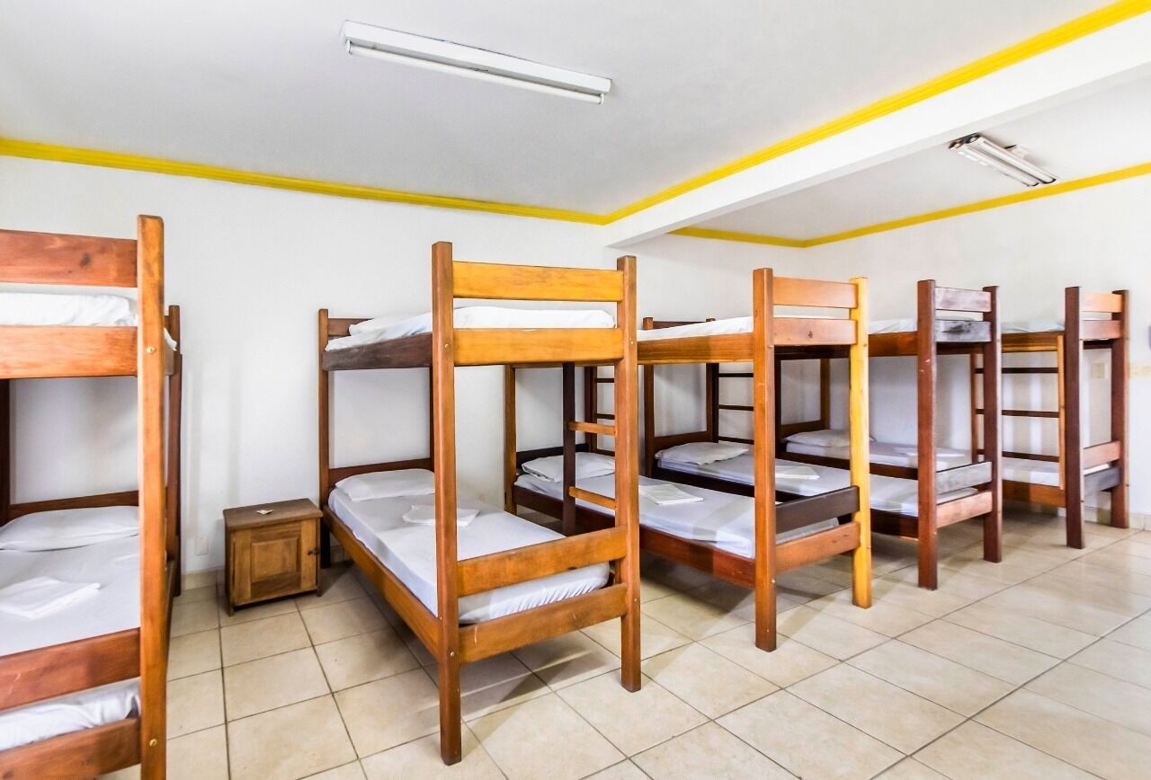 Un dormitorio con literas, un pequeño armario de madera y una lámpara en el techo.