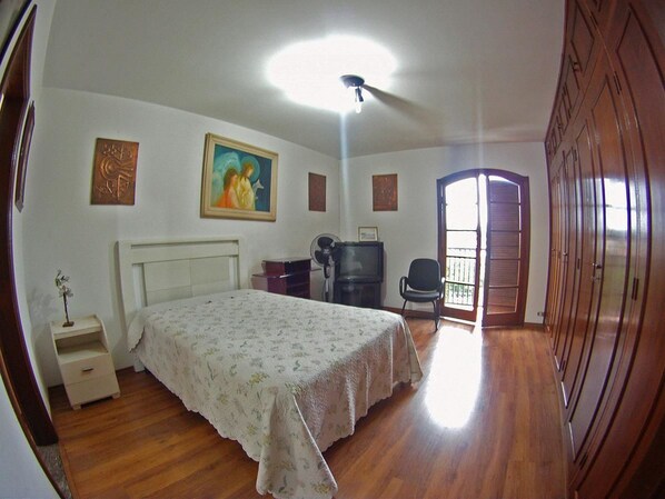 A bedroom with a bed, a desk, a chair, a television, and a wardrobe.