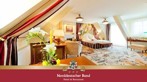 A hotel room with a sloped ceiling, a bed with a white headboard, a desk with a lamp, and a painting on the wall. - Hotel & Restaurant Norddeutscher Bund (Heilbad Heiligenstadt)