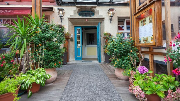 A hotel entrance with a blue door, potted plants, and a wooden walkway. - Hotel & Restaurant Norddeutscher Bund (Heilbad Heiligenstadt)