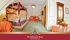 A room with a four-poster bed, a small table with a fruit bowl, and a chair. - Hotel & Restaurant Norddeutscher Bund (Heilbad Heiligenstadt)