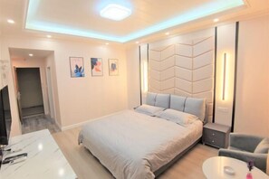 Une chambre d’hôtel moderne, dotée d’un grand lit, de tables de chevet, d’un bureau et d’une chaise.