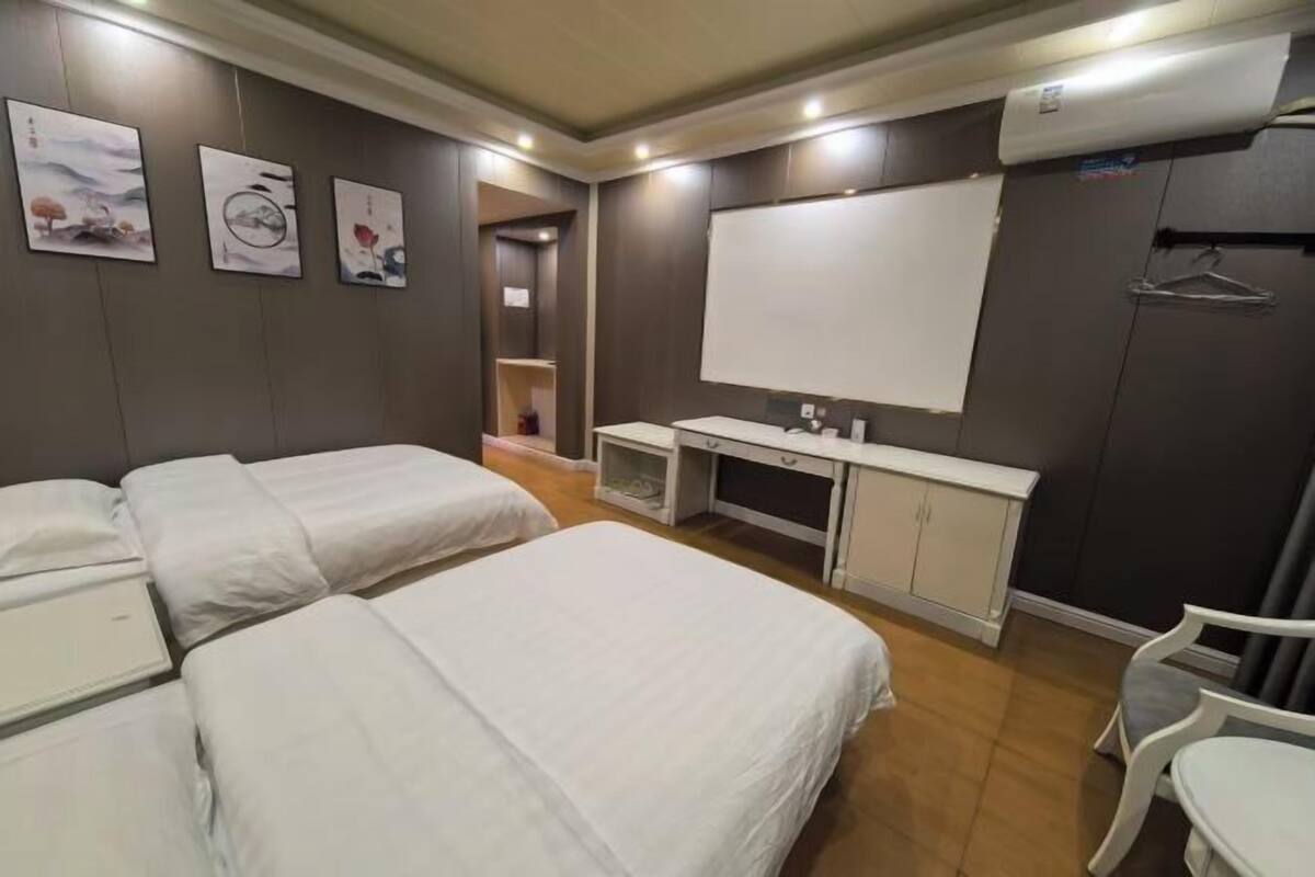 A hotel room with two beds, a desk, a chair, and artwork on the walls.