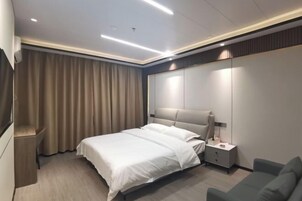 Una habitación de hotel moderna con cama, mesita de noche, lámpara y un espejo grande.