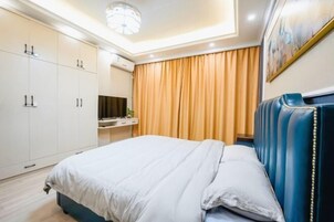 Ett hotellrum med en säng, en tv, en garderob och en tavla på väggen.