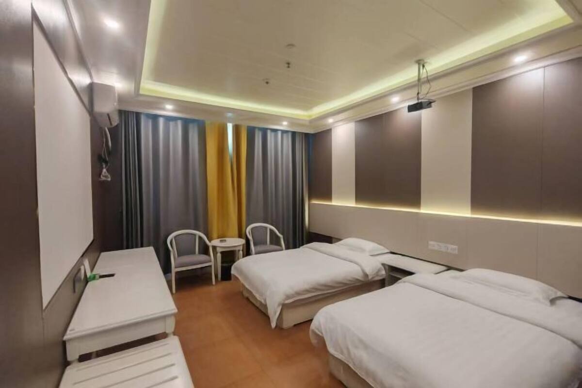A hotel room with two beds, a desk, and a chair.