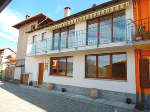 Un immeuble de deux étages doté d’un balcon, de grandes fenêtres et de plantes en pot.