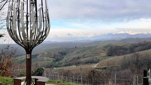 A metal sculpture with a bench in a rural landscape with terraced fields and distant mountains. - Le Colline di Maggiora (Maggiora)