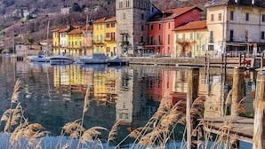 A waterfront with colorful buildings, a dock with boats, and a hill in the background. - Le Colline di Maggiora (Maggiora)