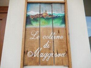 A wooden sign with a painted landscape and the text "Le colline di Maggiora". - Le Colline di Maggiora (Maggiora)