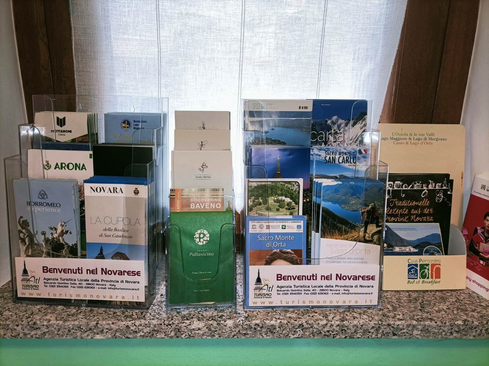 Une exposition de brochures et de cartes touristiques sur Novare, en Italie, comprenant des informations sur les attractions locales et les hébergements.