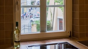 A kitchen with a window, a bottle of liquor, and a stovetop. - ApartOne (Bautzen)