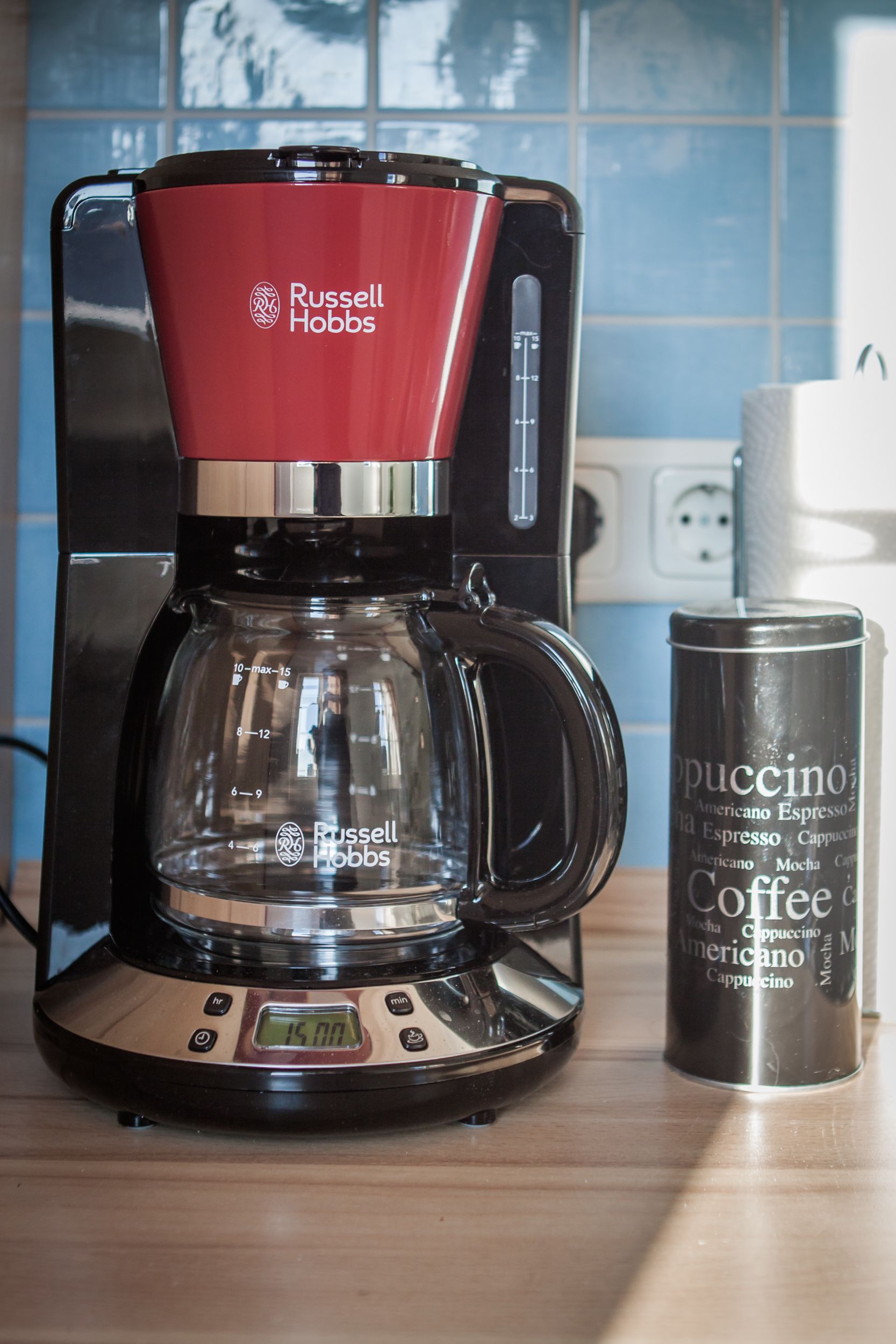 A Russell Hobbs coffee maker with a clear glass carafe and a stainless steel mug labeled "Puccino Coffee Americano."