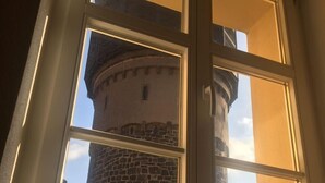A window with a view of a stone tower and a round building. - ApartOne (Bautzen)