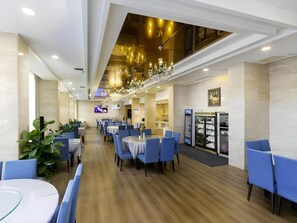 A modern dining area with round tables and blue chairs, a chandelier, and a glass display case with plates. - Vienna Classic Hotel (Shangrao Pedestrian street Peace Sunshine) (Shangrao)