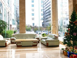 A lobby with a seating area, a Christmas tree, and a view of the cityscape through large windows. - Vienna Classic Hotel (Shangrao Pedestrian street Peace Sunshine) (Shangrao)