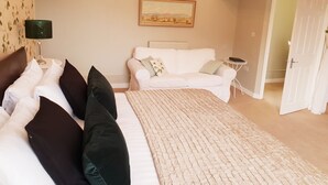 Ett sovrum med en säng, en vit soffa och en tavla på väggen.