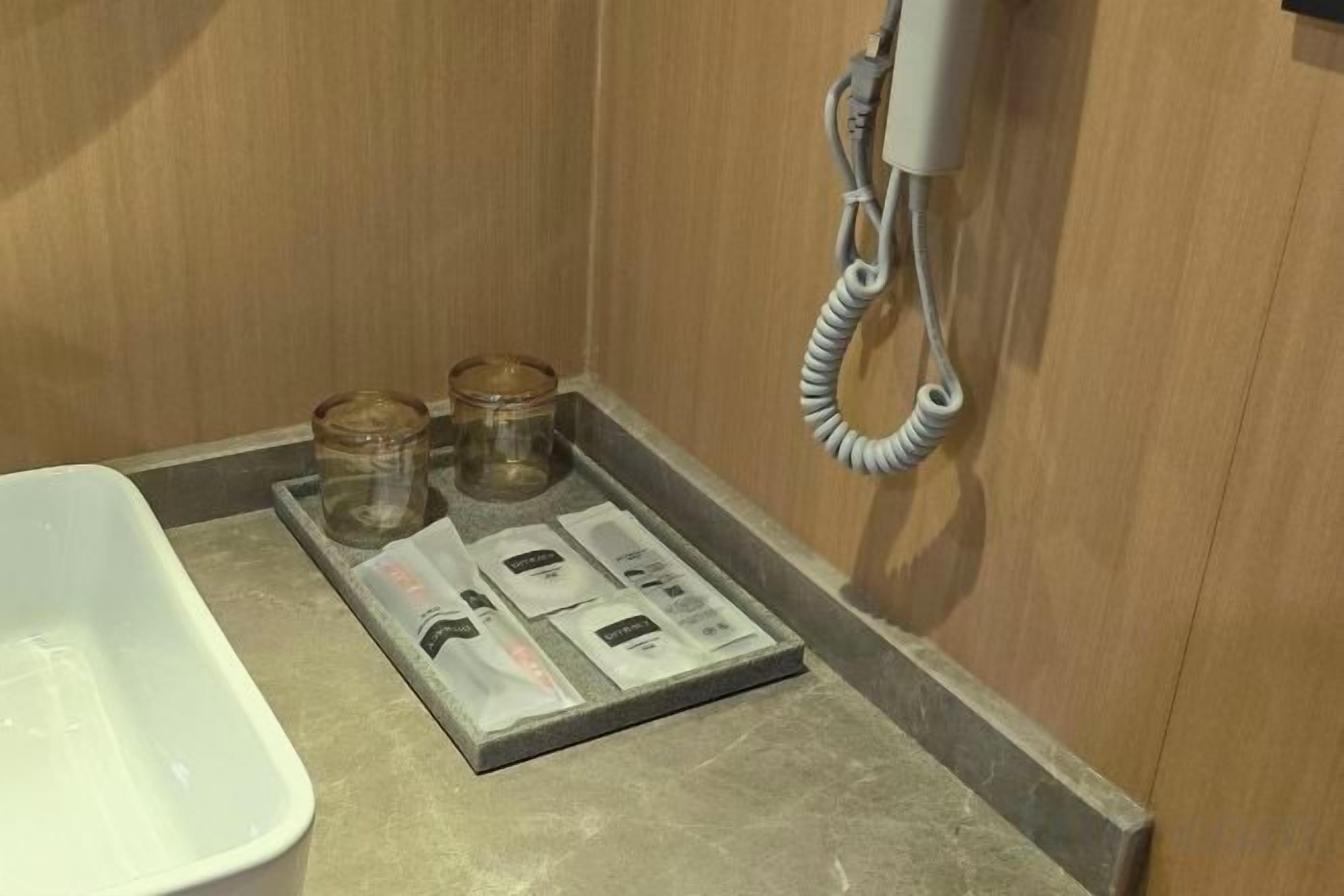 Un baño con una bañera blanca, un perchero para toallas y un juego de artículos de aseo en una bandeja.