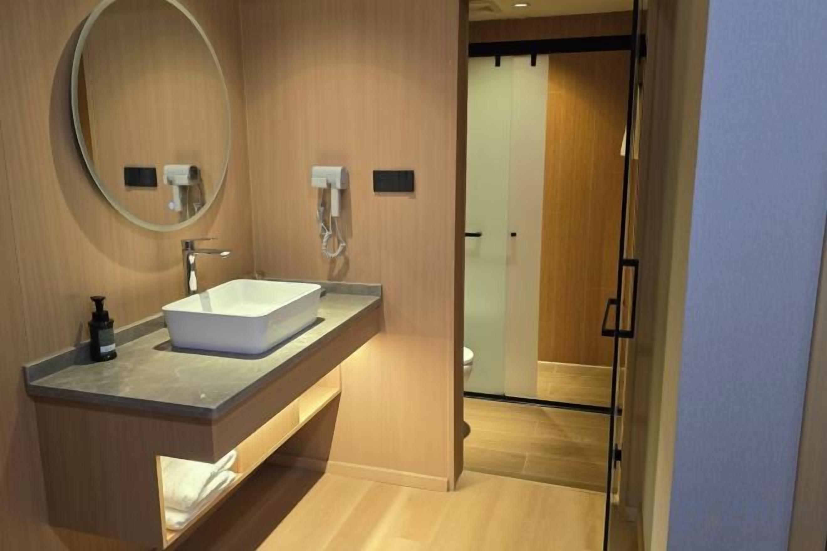 A modern bathroom with a large mirror, a rectangular sink, and a towel rack.