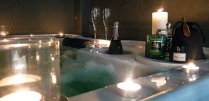 Un bain à remous avec des bougies, un flacon de parfum et une bouteille de champagne.
