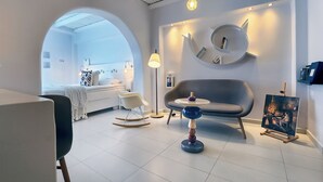 Una sala de estar moderna con un sofá, un sillón mecedor, una mesita y un cuadro en la pared.