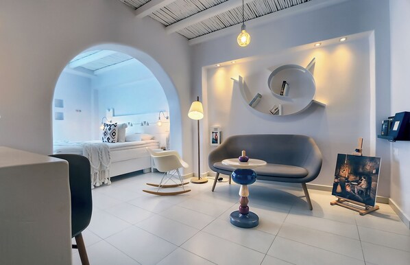 Un salon moderne avec un canapé, un fauteuil à bascule, une petite table et un tableau accroché au mur.