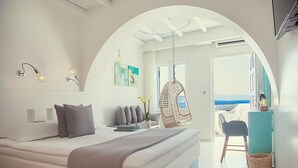 Un dormitorio moderno con una cama grande, una silla colgante y vistas al mar.