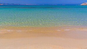 Ein Strand mit klarem, flachem Wasser und einem sandigen Ufer.