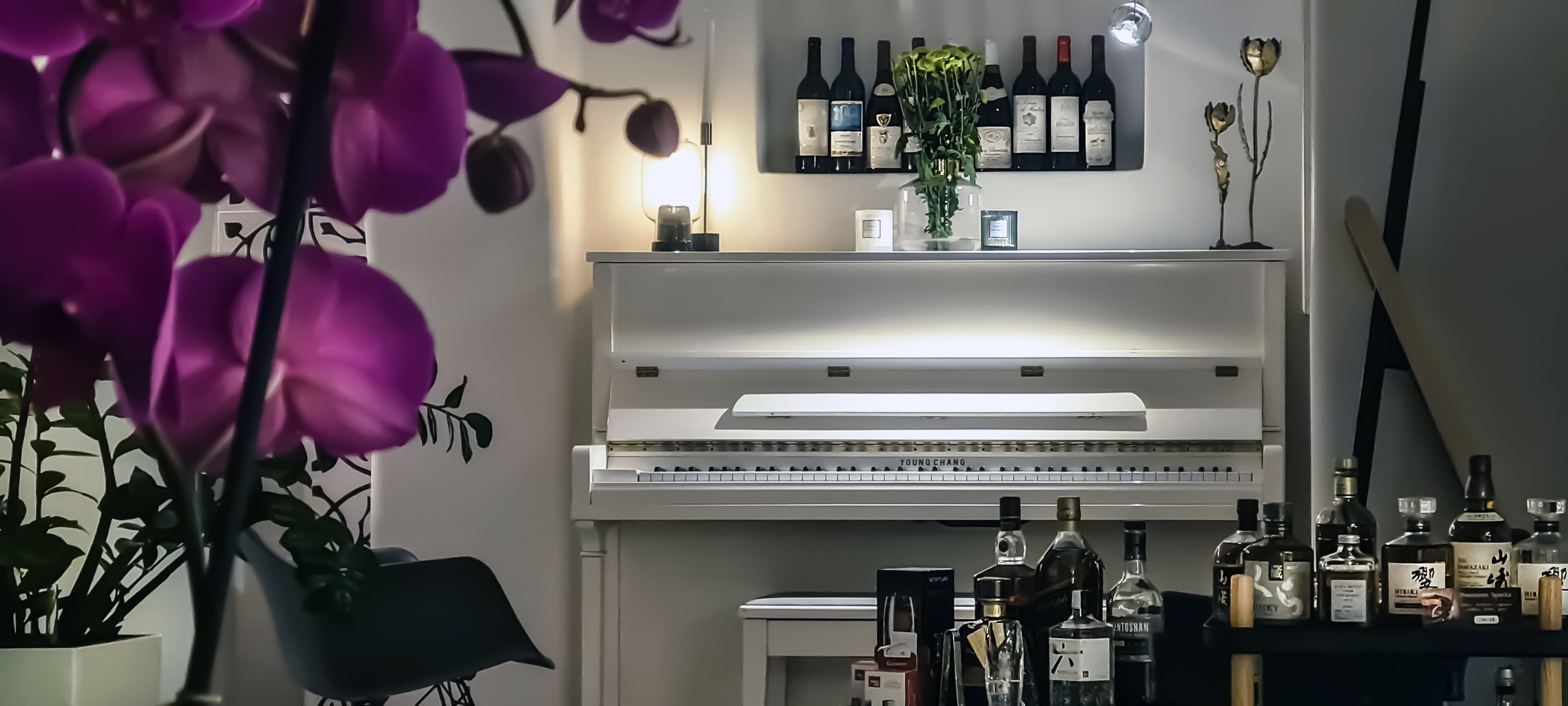 Une pièce avec un piano, un meuble à bouteilles et différentes bouteilles disposées sur une étagère.