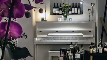 Une pièce avec un piano, un meuble à bouteilles et différentes bouteilles disposées sur une étagère.
