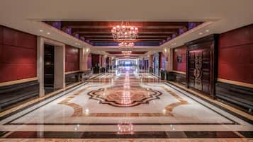 A hotel corridor with a grand chandelier, marble flooring, and a large number '5' in the center.