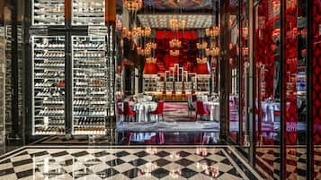 Un hall de hotel con piso a cuadros, botelleros, una zona de comedor y un candelabro.