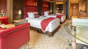 A hotel room with two beds, a sitting area with a red chair, a glass table, and a bathroom visible through an open door. - Jinjiang International Hotel Ganzhou (GANZHOU)