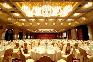 Un salón de banquetes con mesas redondas, manteles blancos y sillas.