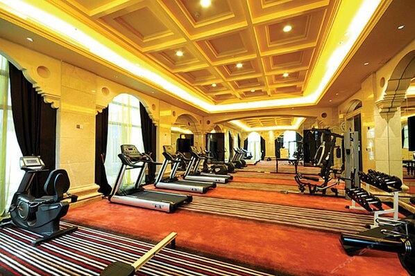 Un gimnasio de hotel con cintas de correr, bicicletas estáticas y máquinas de pesas.