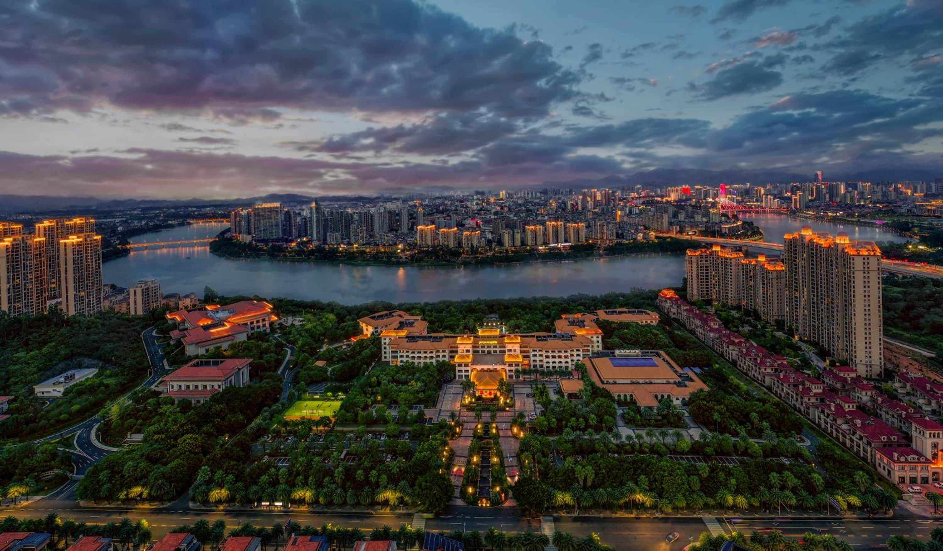 A cityscape with high-rise buildings, a river, and a well-lit central plaza.