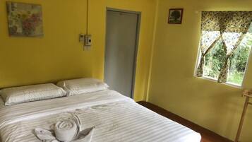 A hotel room with a bed, a door, a window with a view, and a wall-mounted phone.