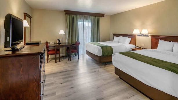 A hotel room with two beds, a desk with a TV, a chair, and a window with curtains. - Quality Inn & Suites El Cajon San Diego East (El Cajon)