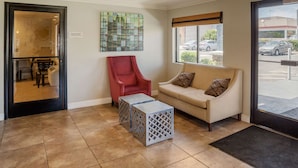 A reception area with a red chair, a beige sofa, and two cube-shaped side tables. - Quality Inn & Suites El Cajon San Diego East (El Cajon)