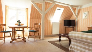 Une pièce comprenant un lit, une table avec des chaises, un téléviseur et un radiateur.
