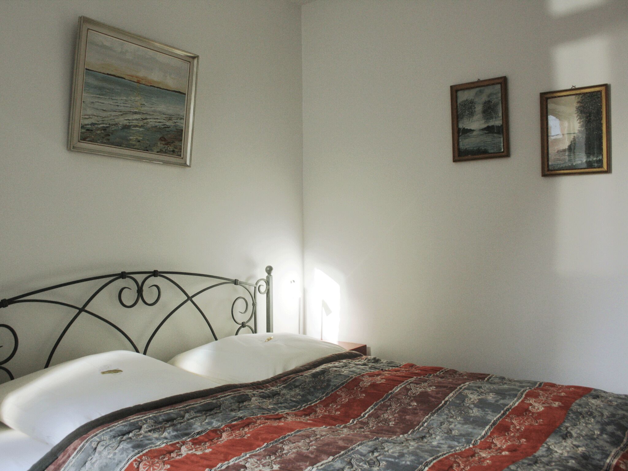 Una camera da letto con un letto, un quadro appeso al muro e due immagini più piccole incorniciate.