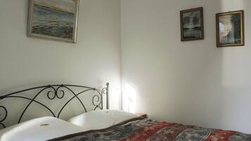 Una camera da letto con un letto, un quadro appeso al muro e due immagini più piccole incorniciate.