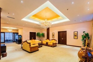 A spacious lobby with a high ceiling, a chandelier, and a seating area with sofas and armchairs.