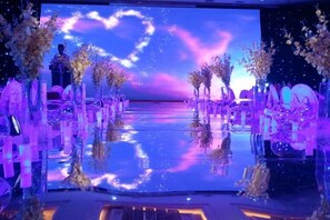 Un espacio con piso reflectante, hileras de sillas y un fondo con diseño de corazón.