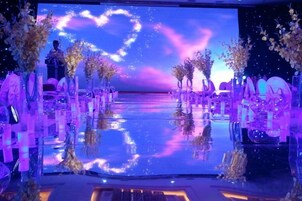 Un espacio con piso reflectante, hileras de sillas y un fondo con diseño de corazón.