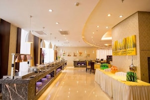 Un vestíbulo de hotel con una larga mesa de buffet, una zona de estar y una recepción.