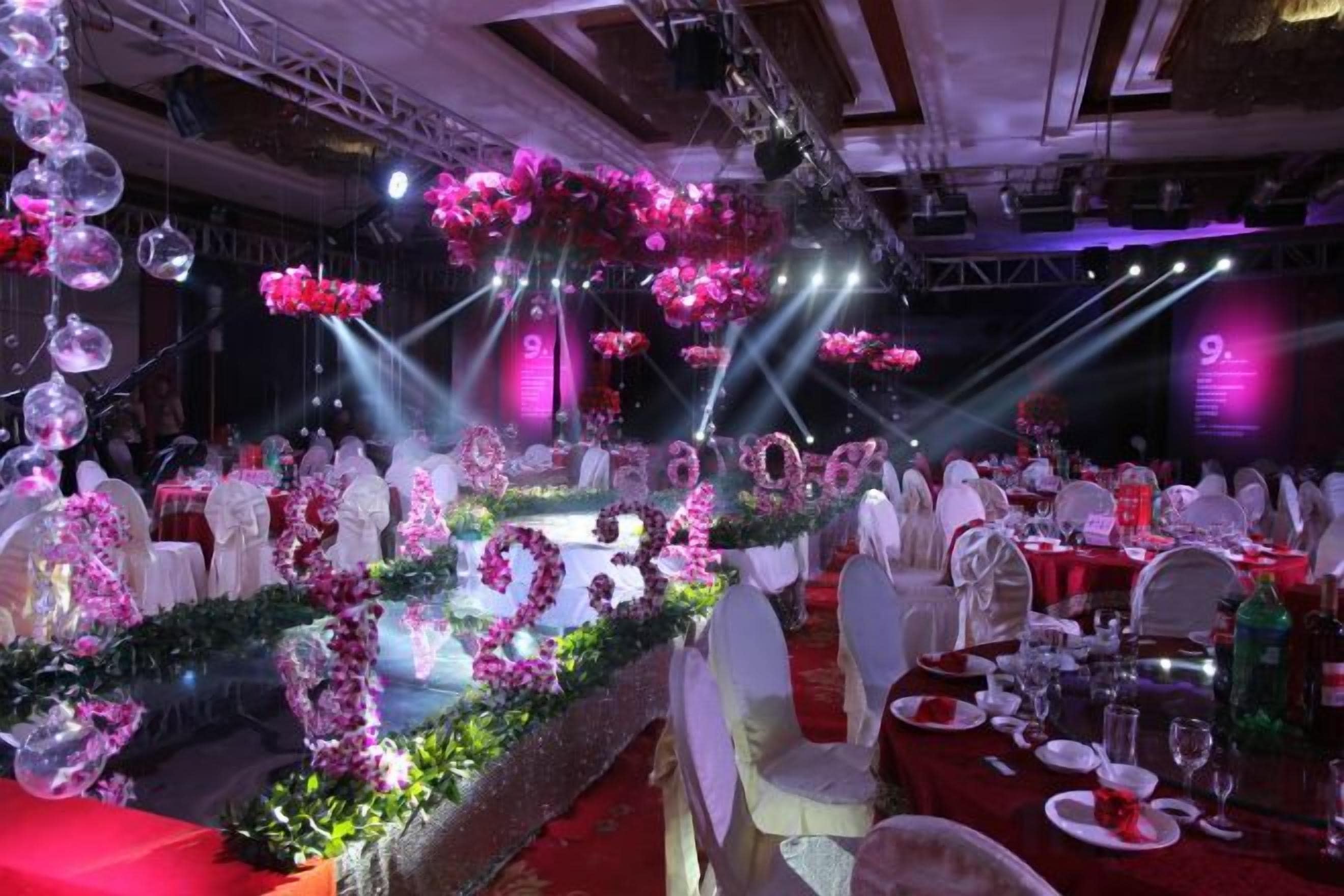 Een balzaal met ronde tafels, stoelen en bloemendecoraties.